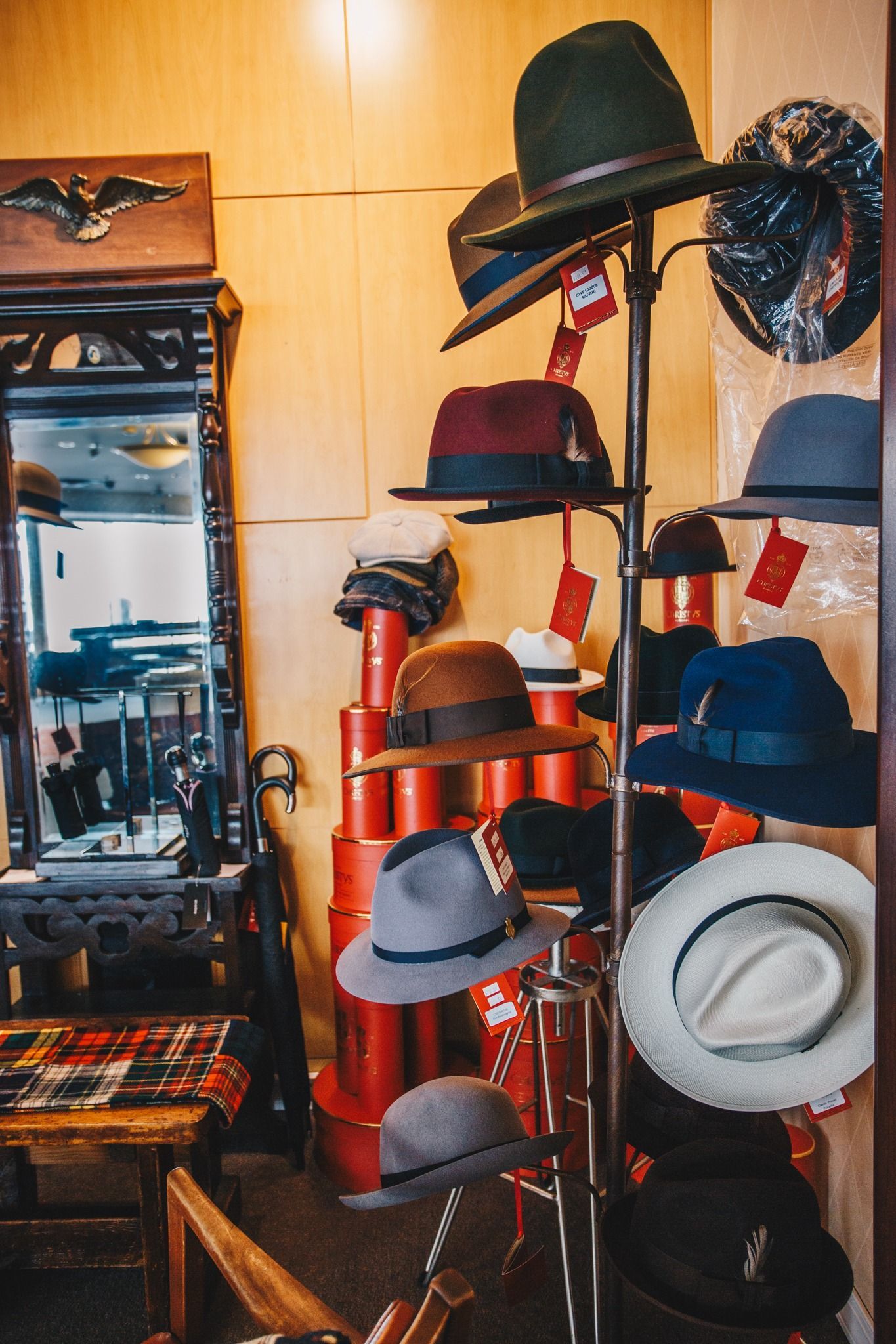 Hat display in a shop, with assorted colorful hats on racks and shelves by a mirror.