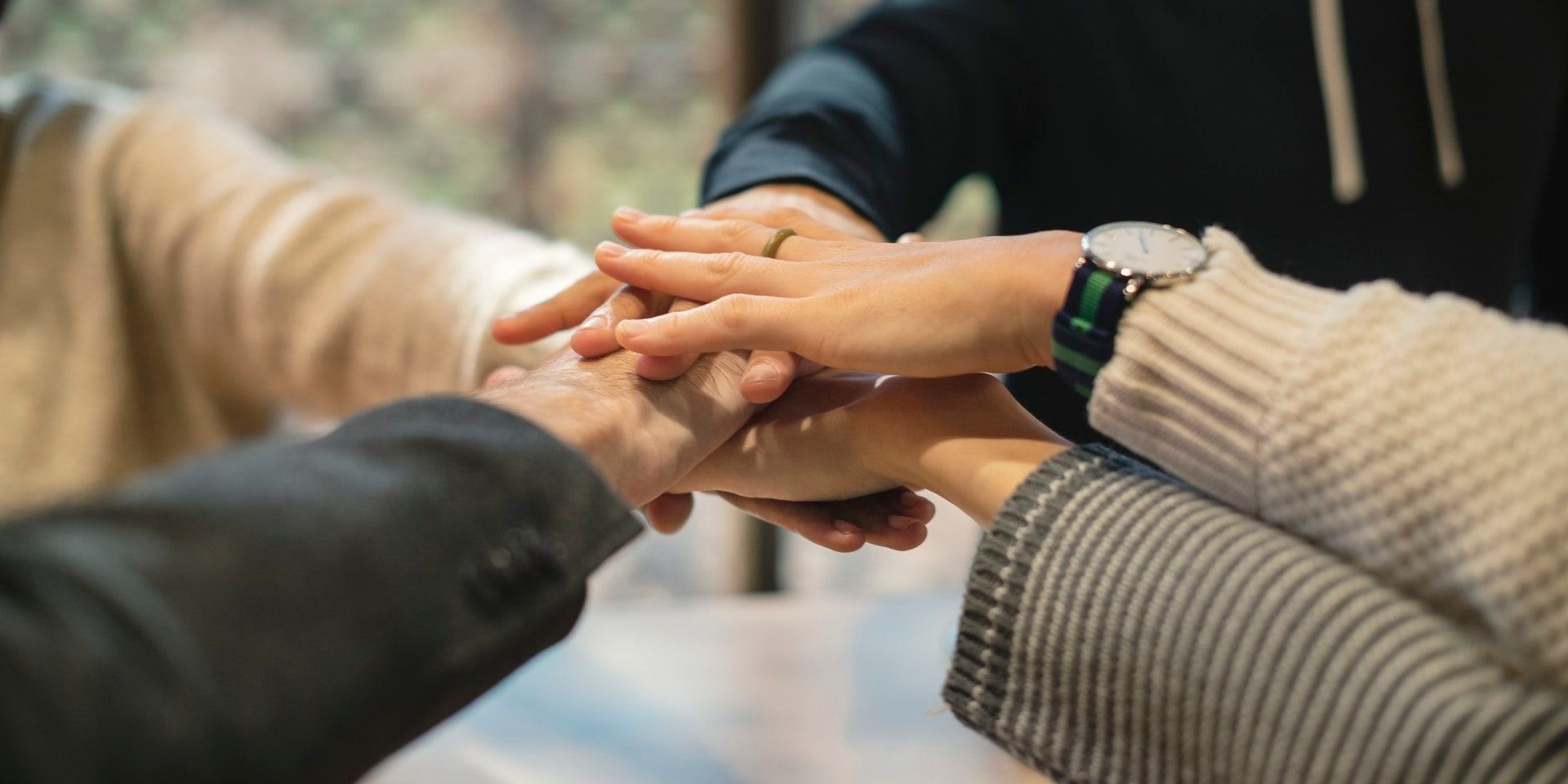 Hands piled on top of each other, symbolizing teamwork and collaboration.