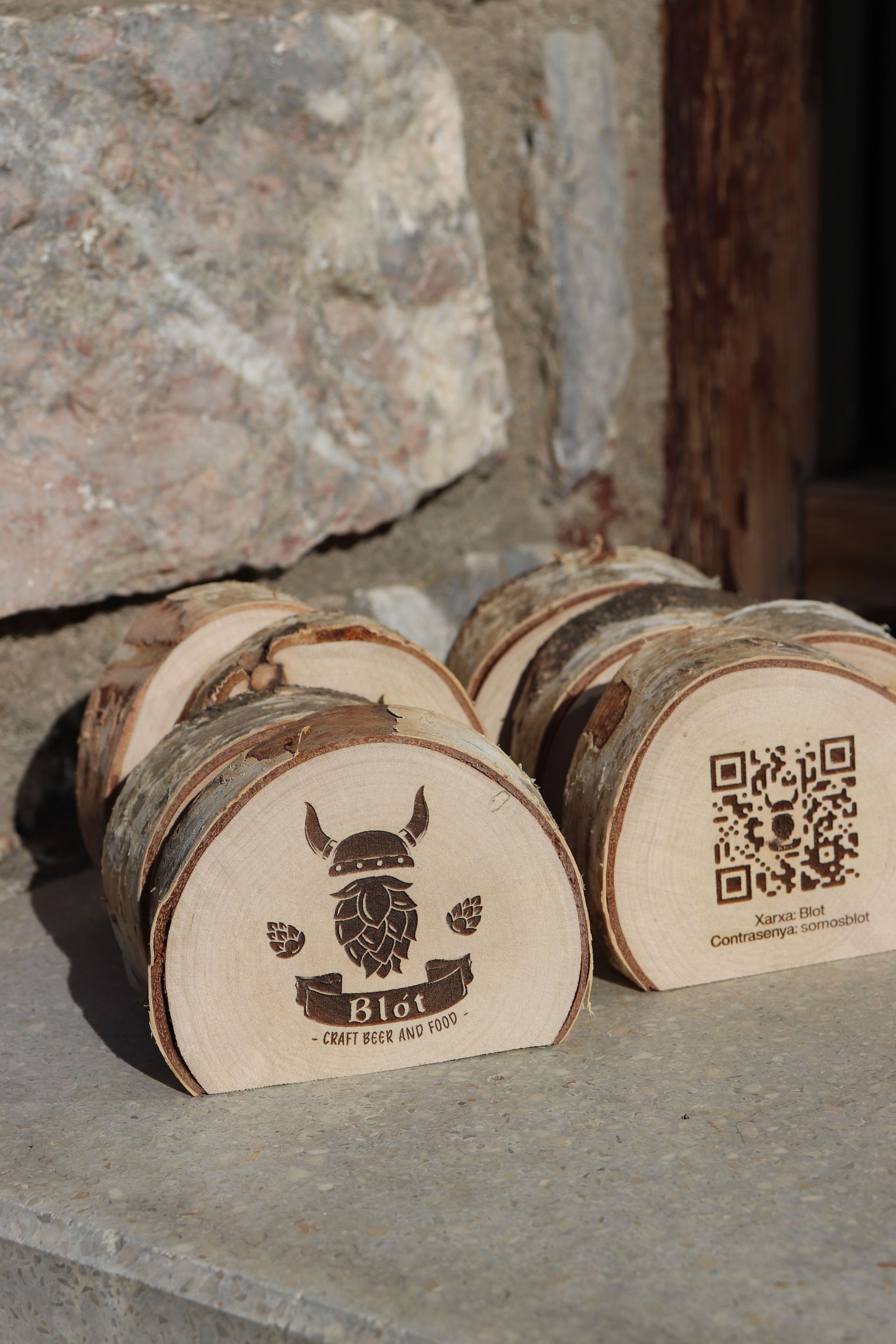 Un par de rodajas de madera de abedul grabadas  a láser con el logotipo de Blot hecho por Mersi Studio