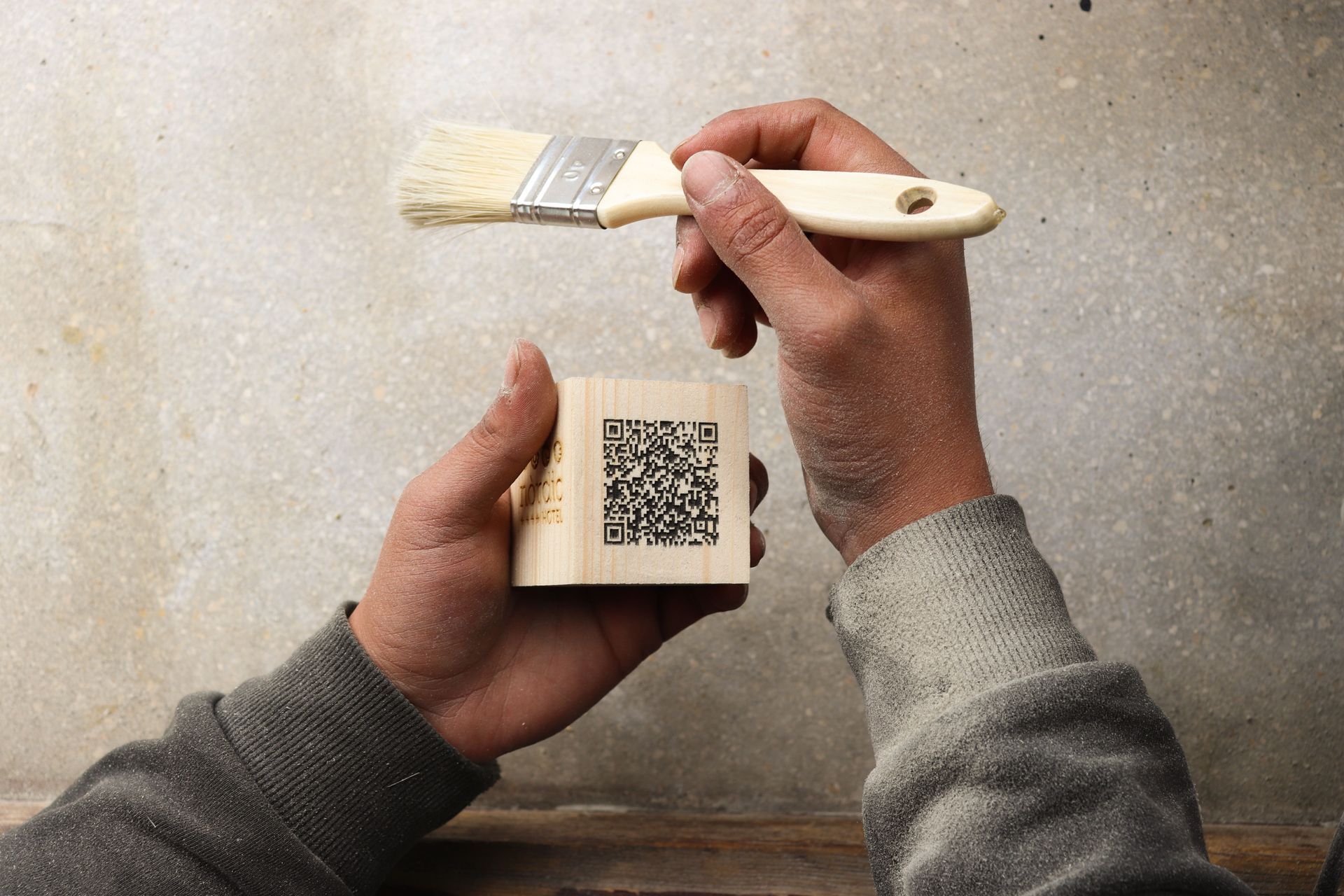 Una persona del estudio de Mersi Studio sostiene un pinzel con un codigo QR para un restaurante. 