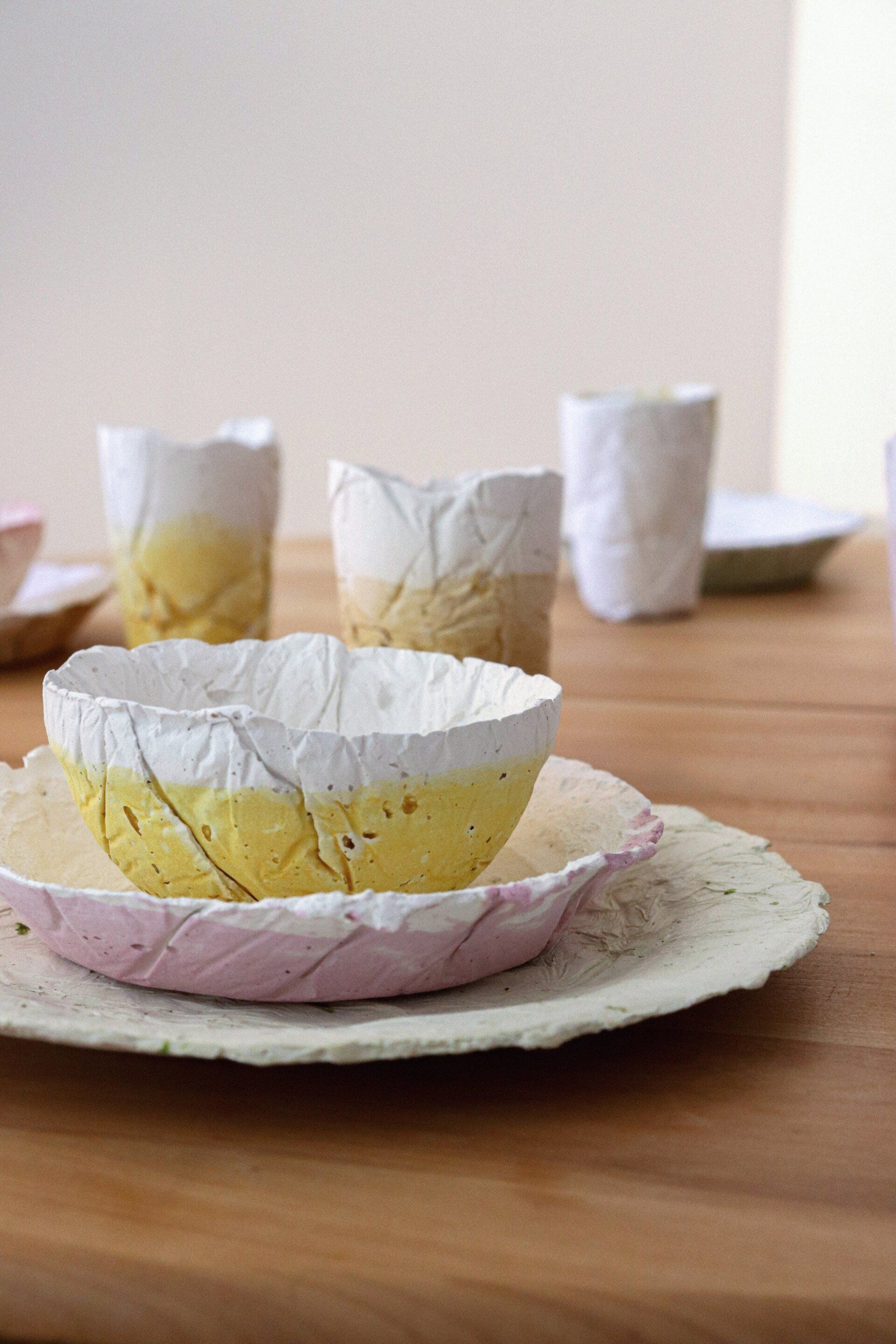 Fotografia dels productes final del projecte egg dishes fets amb biomaterial. Recolzats sobre una taula de fusta i fons blanc. Dissenyat per mersi studio.