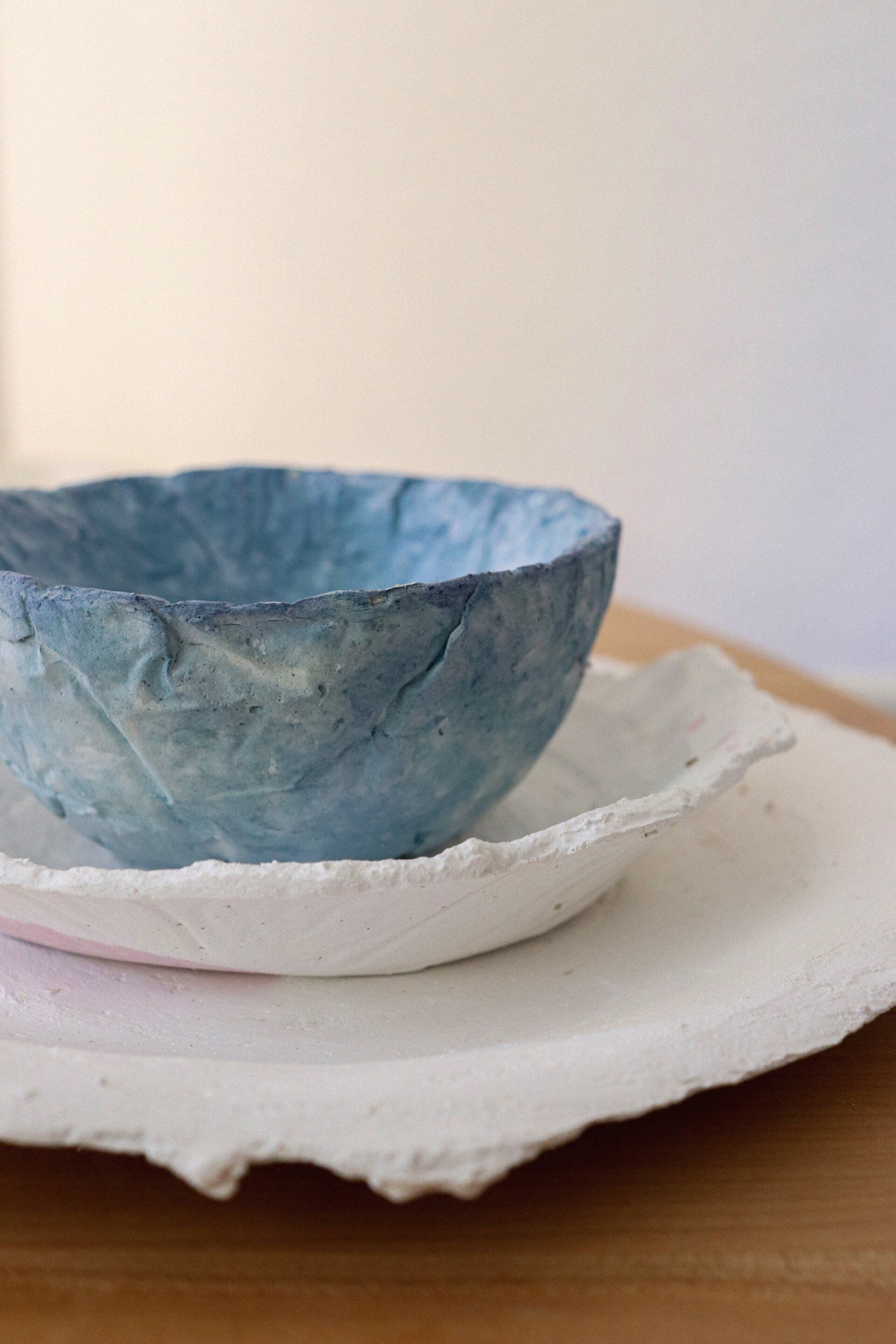 Fotografia dels productes final del projecte egg dishes fets amb biomaterial. Recolzats sobre una taula de fusta i fons blanc. Dissenyat per mersi studio.