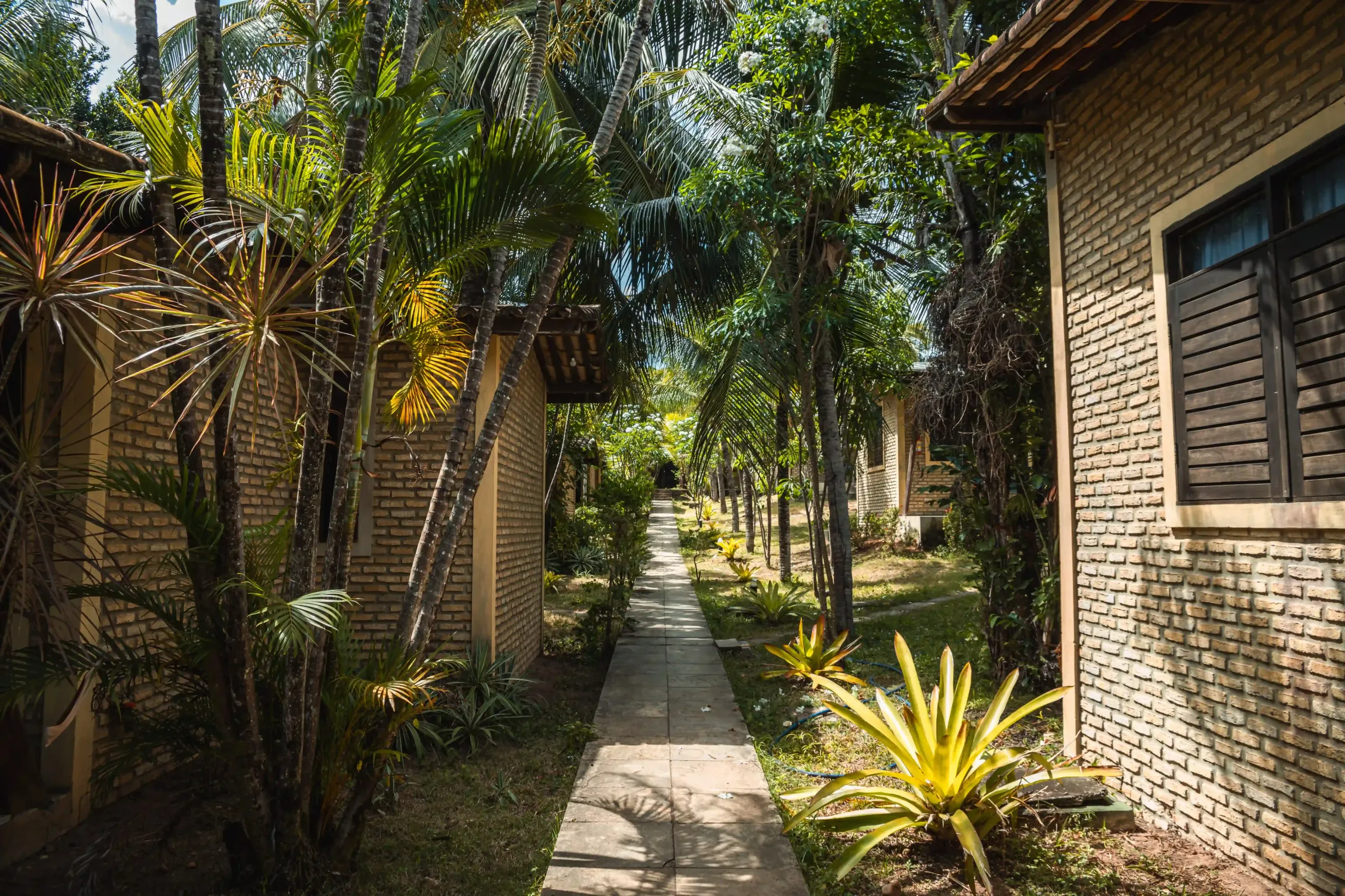 Um caminho que leva a uma fileira de casas de tijolos cercadas por árvores.-Pousada-Imperio-do-Sol