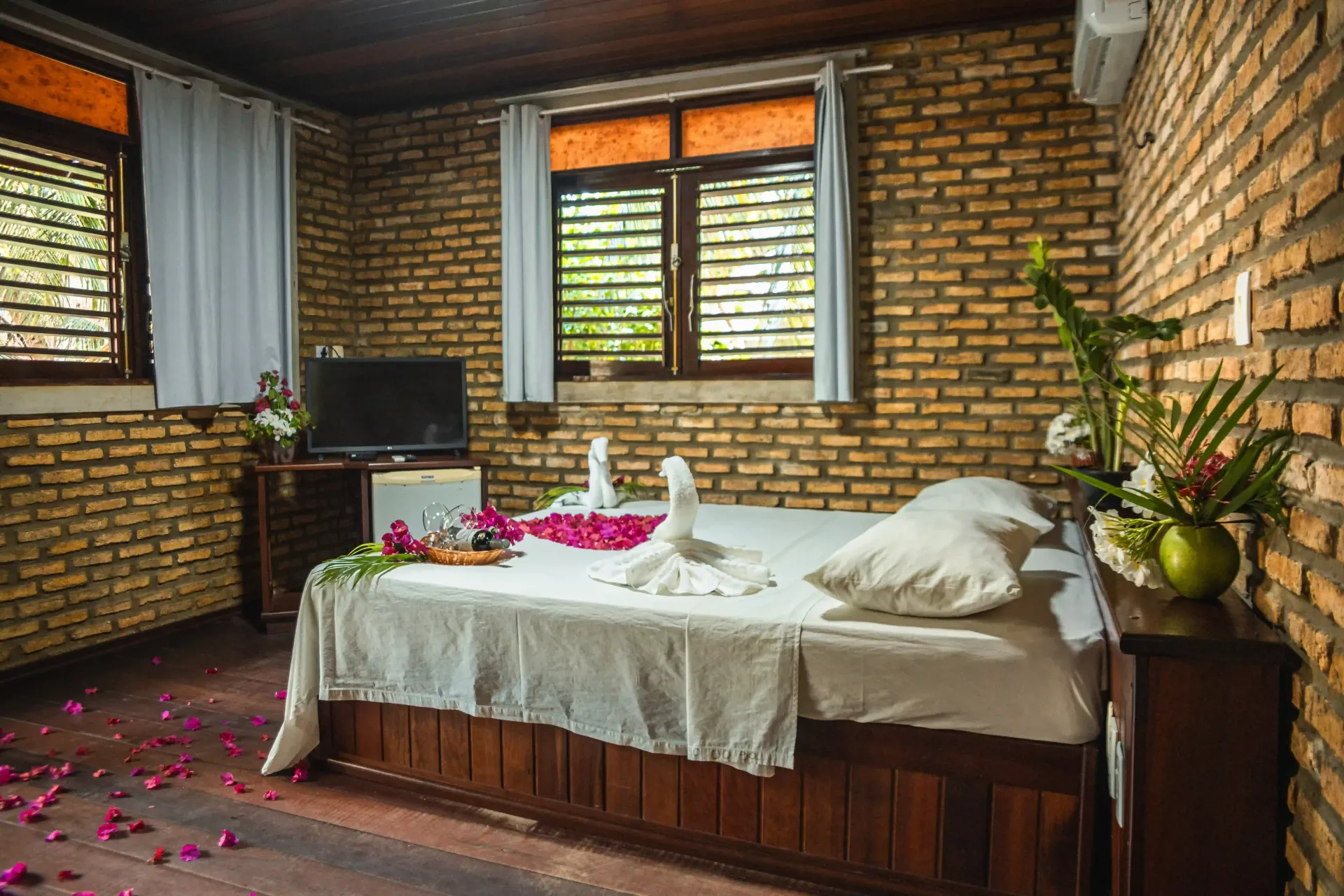 Um quarto com uma cama, uma televisão e uma parede de tijolos.-Pousada-Imperio-do-Sol