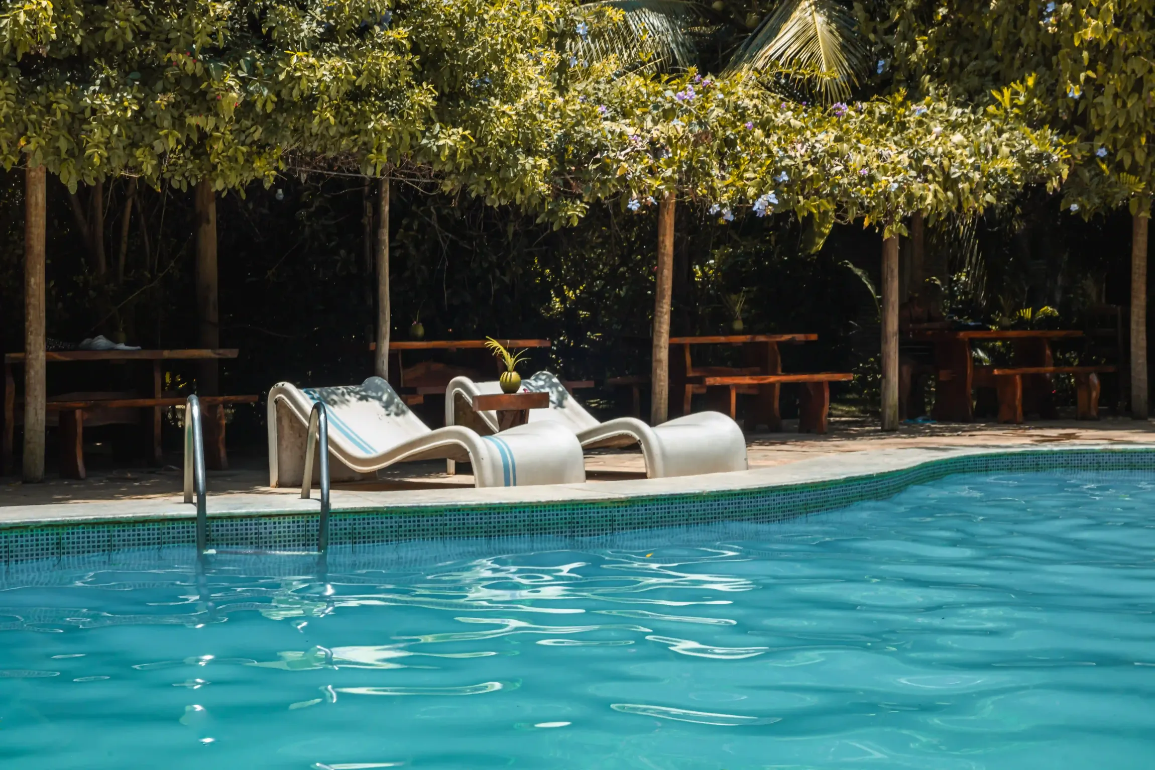 Uma piscina com cadeiras e mesas ao redor.-Pousada-Imperio-do-Sol