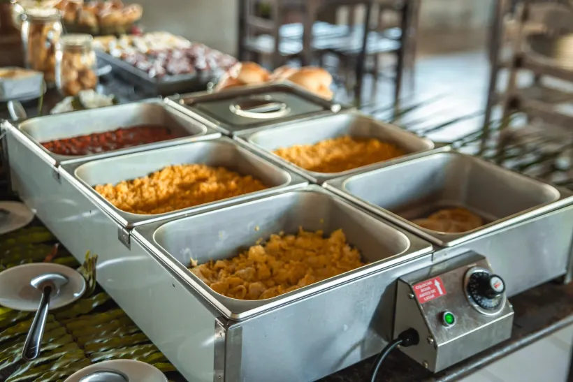 Uma mesa de bufê com várias bandejas de comida em cima.-Pousada-Imperio-do-Sol