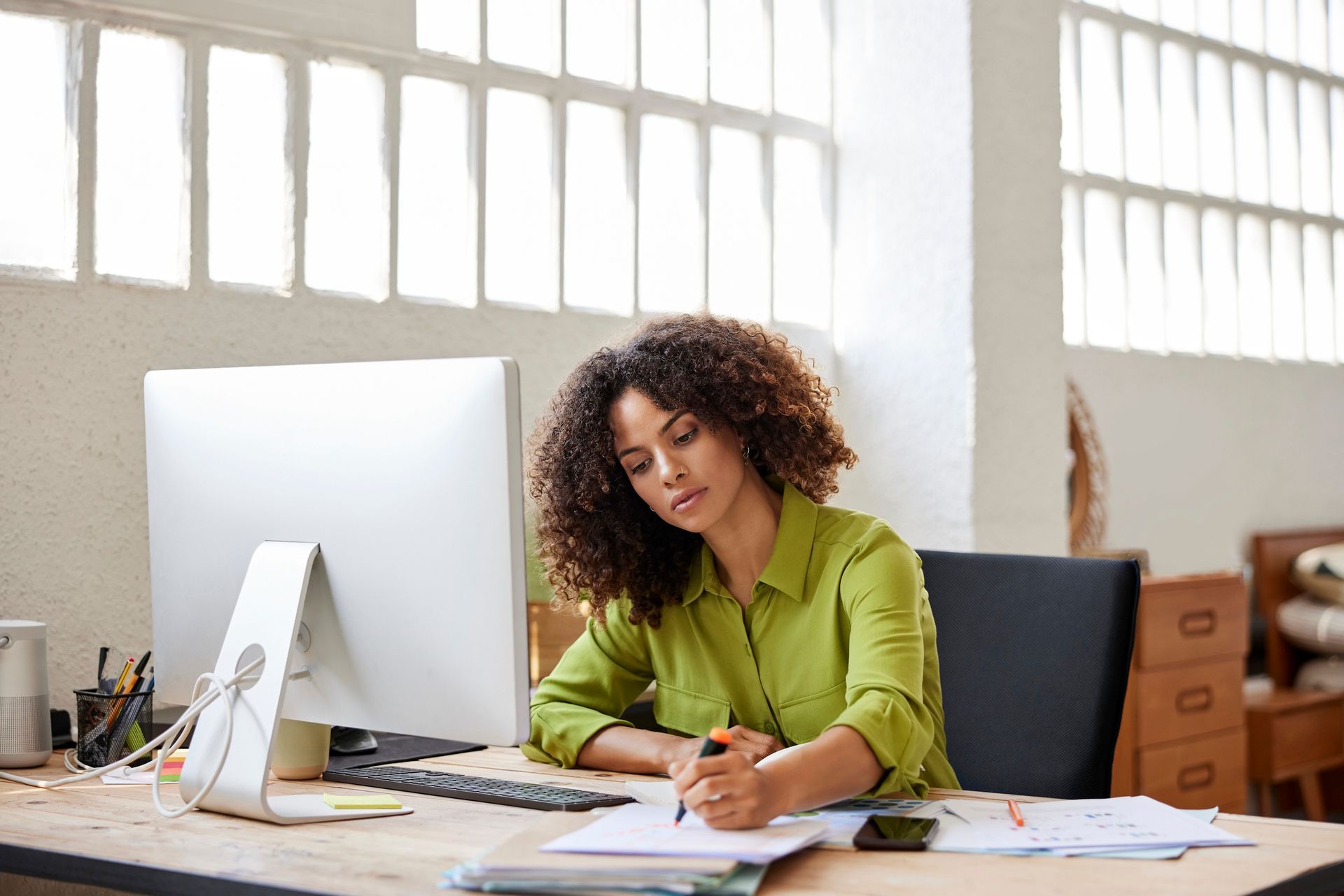 A woman is sitting at a desk in front of a computer.