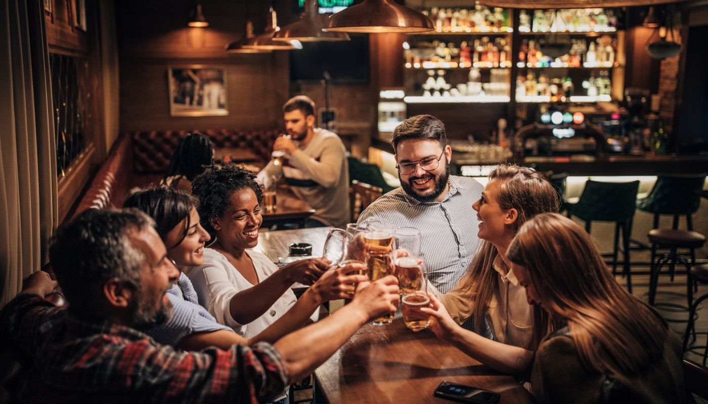 Group of friends celebrating together in a warm pub, showcasing one of the top businesses that boom in winter.