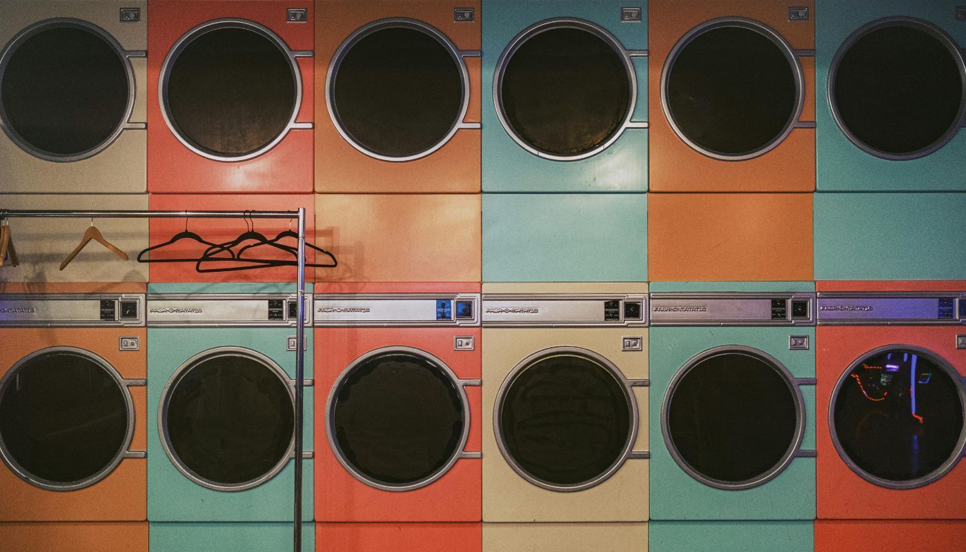Colorful row of vintage laundry machines and hanging clothes in a laundromat built to help owners earn passive income