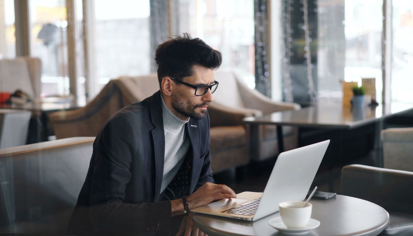 Focused businessman working on a laptop, exploring franchise development over coffee