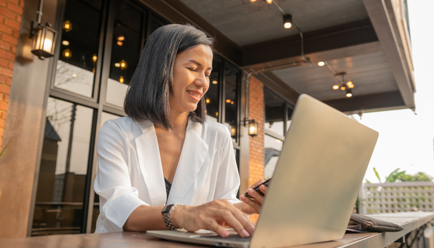 Cafe owner using a laptop and mobile phone while researching a franchise opportunity