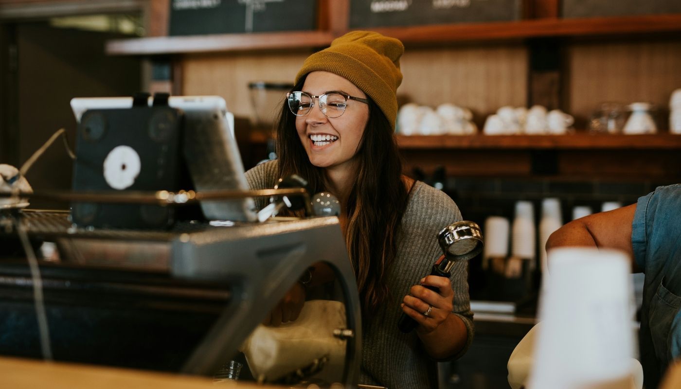 Happy barista using a coffee machine as part of franchise ownership
