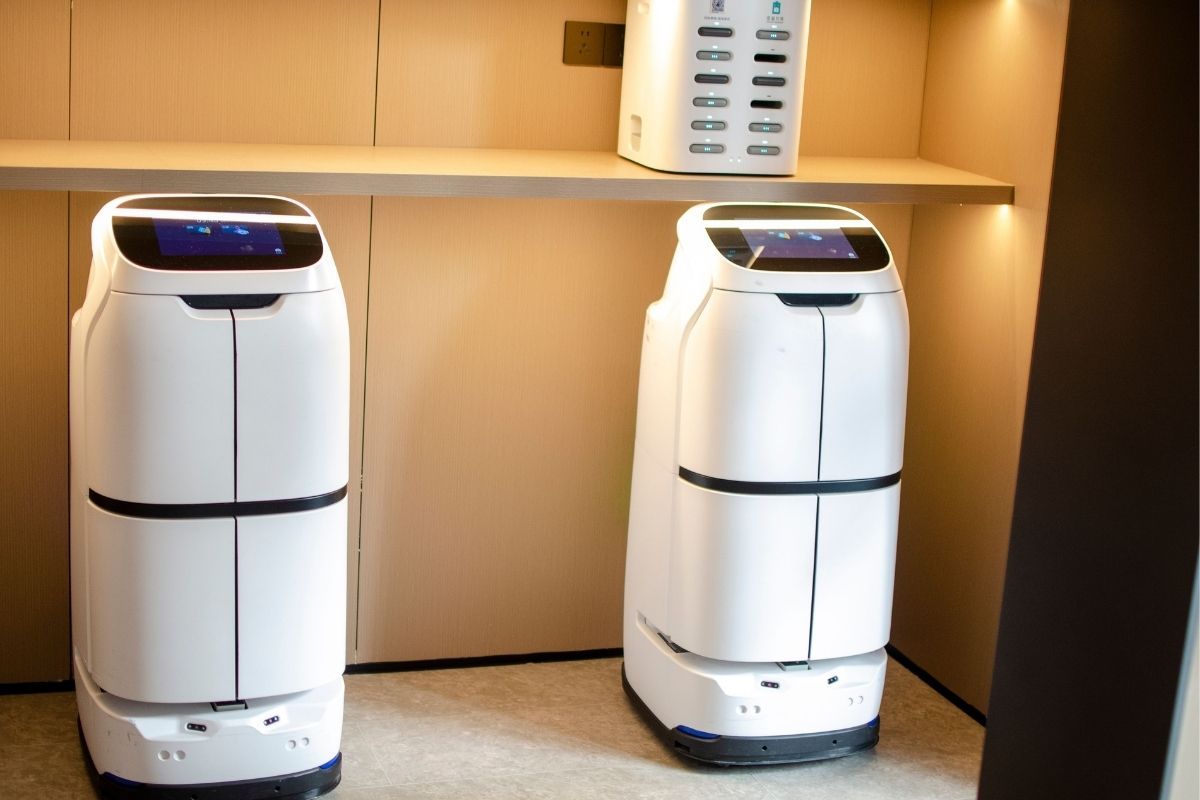 Two white robotic delivery systems located in a restaurant, showing how AI affects franchise businesses