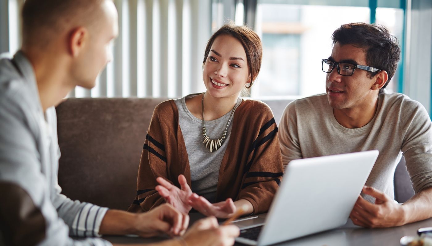 A man and a woman are sitting at a table with a laptop.