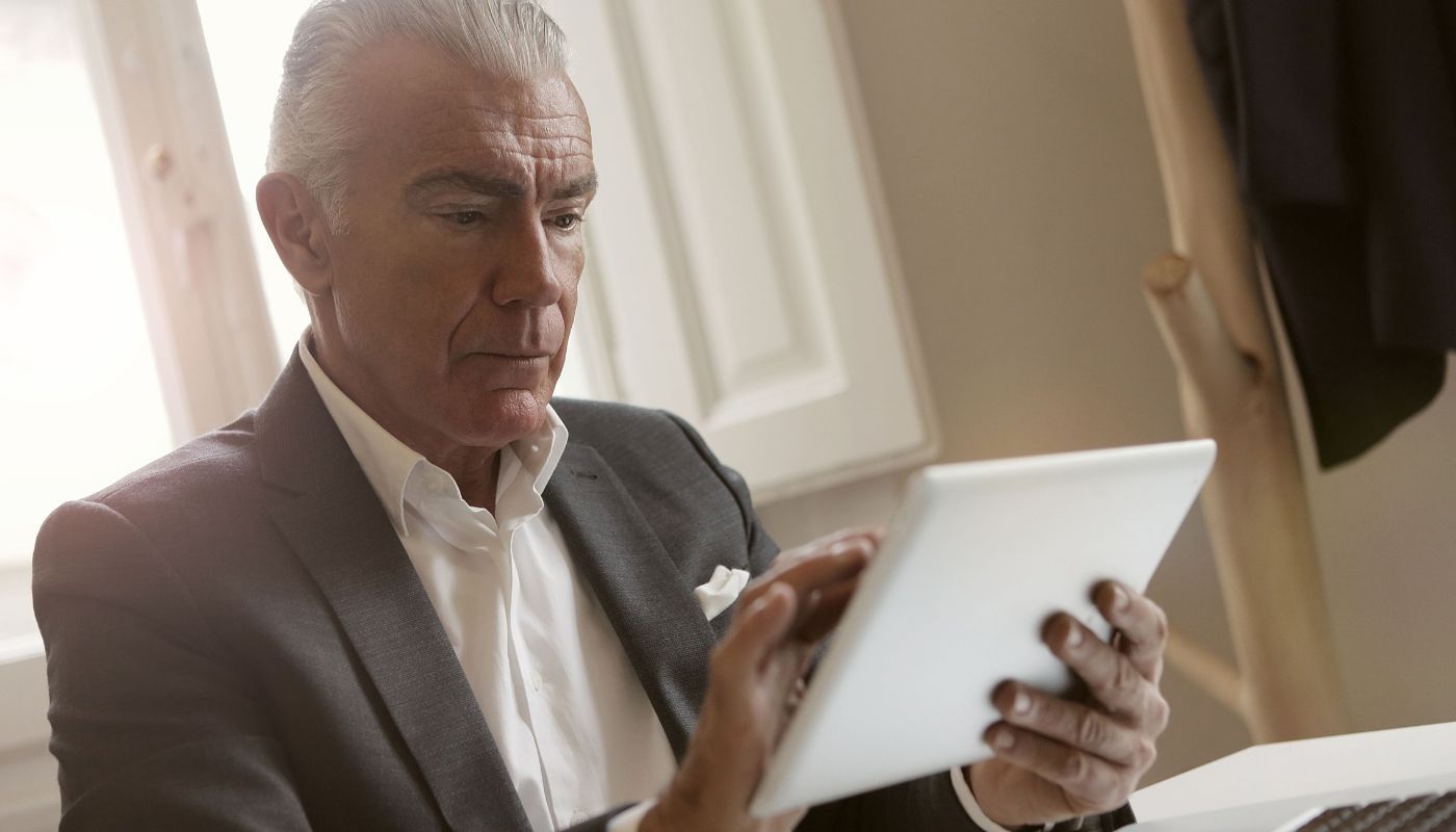 businessman focused on using a tablet while researching how to tell if a franchise is a good investment