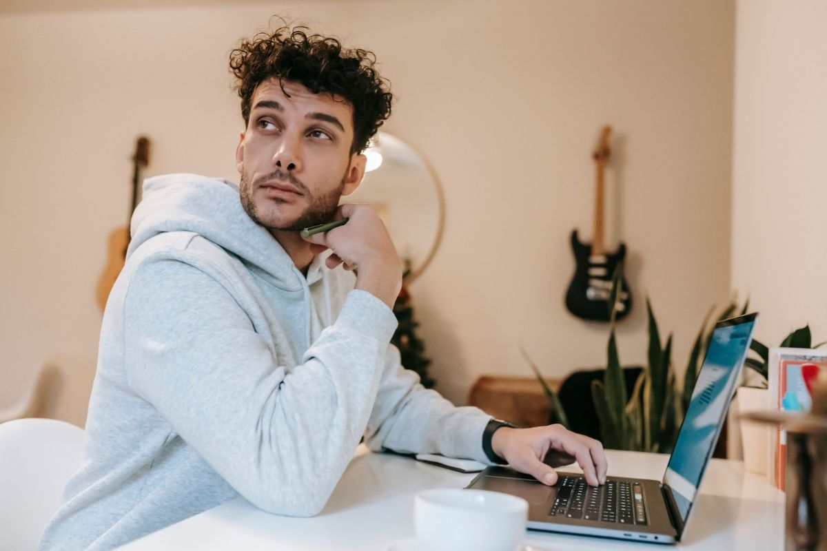 Man in a hoodie working in a laptop, thinking about whether now is a good time to buy a franchise
