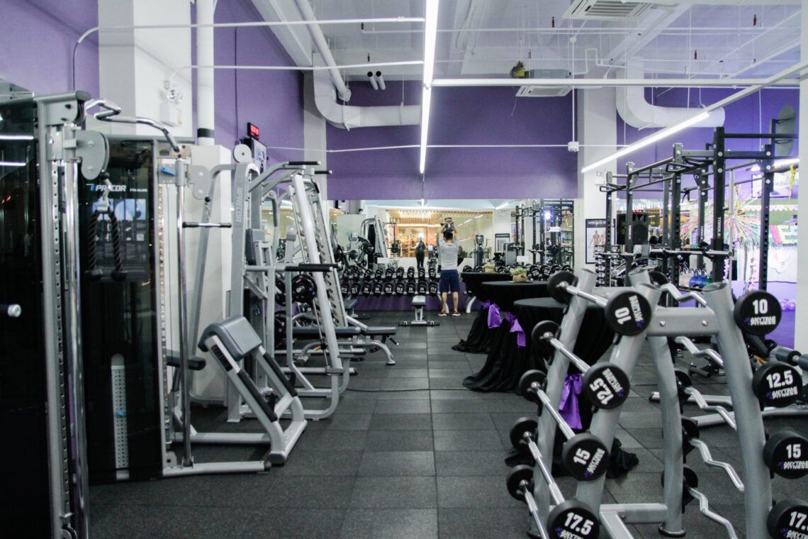 A gym filled with lots of dumbbells and exercise equipment.
