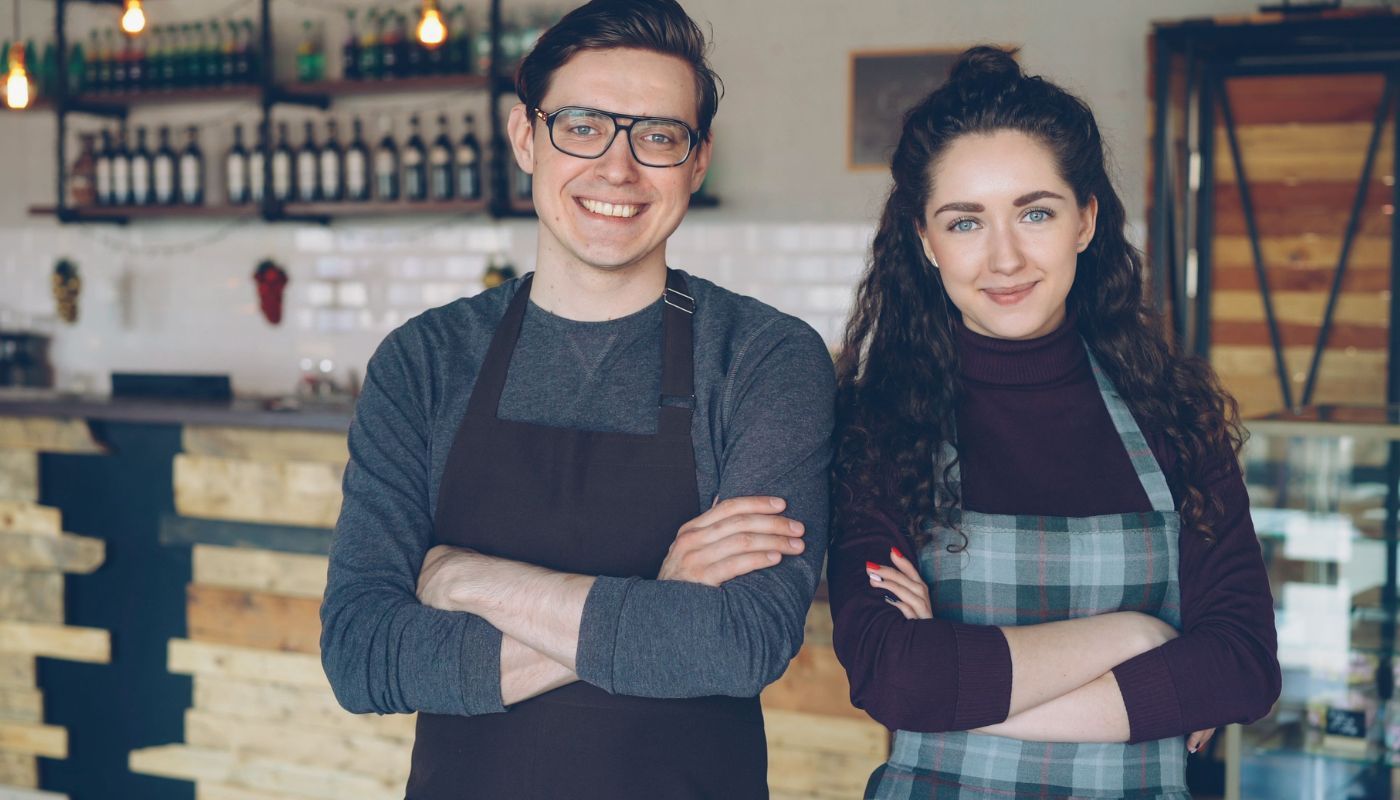 Two millennial franchise owners standing proudly in their modern café