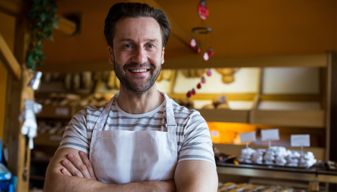 Smiling owner standing in bakery shop representing a profitable franchise business
