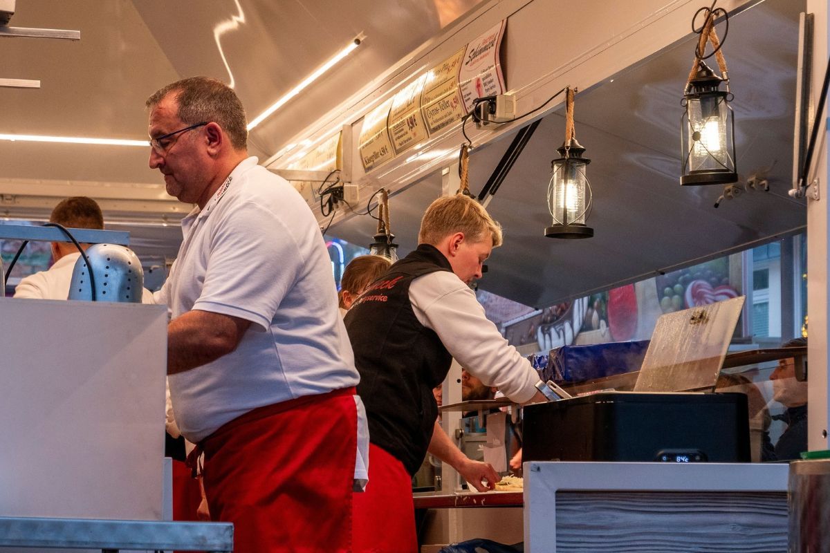 Man preparing meals inside a small franchise food truck