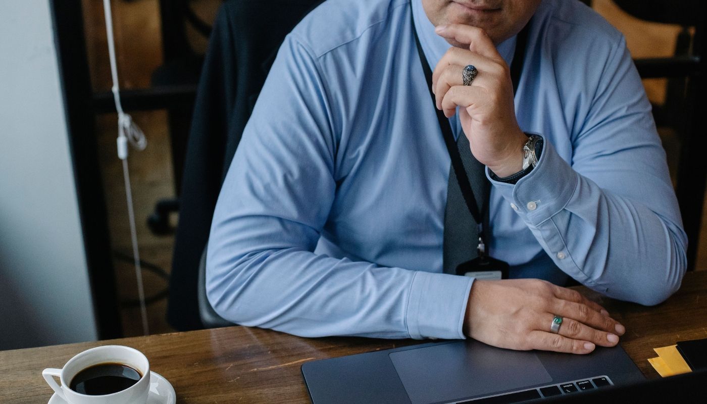Businessman deep in thought, working at a desk with a laptop and coffee, reflecting the traits of a successful franchise owner