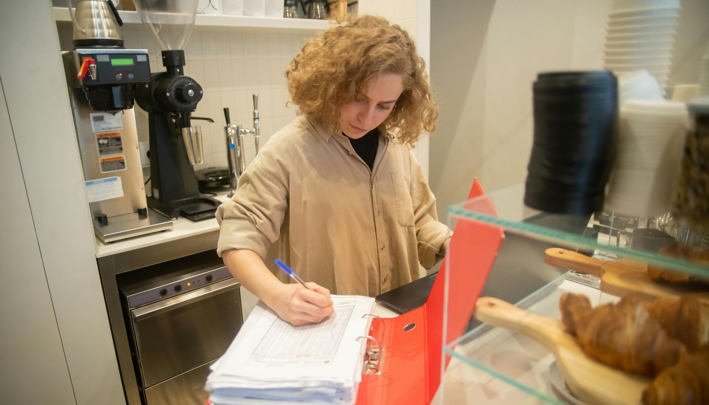 Businesswoman managing inventory and daily operations in a cozy café, showcasing different types of ownership
