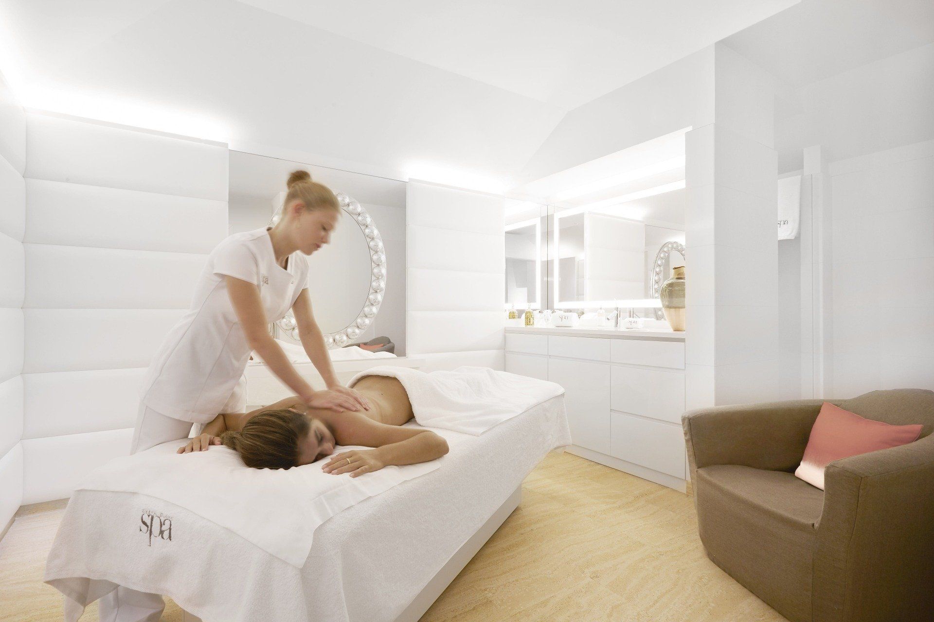 Woman giving a back massage in a white spa setting.