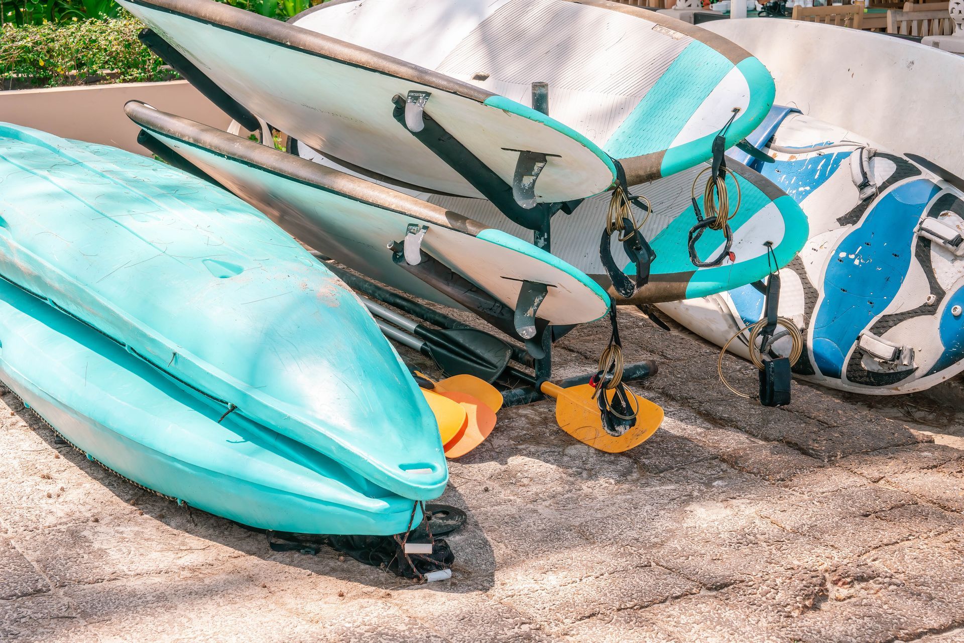 A bunch of surfboards are stacked on top of each other on the beach.