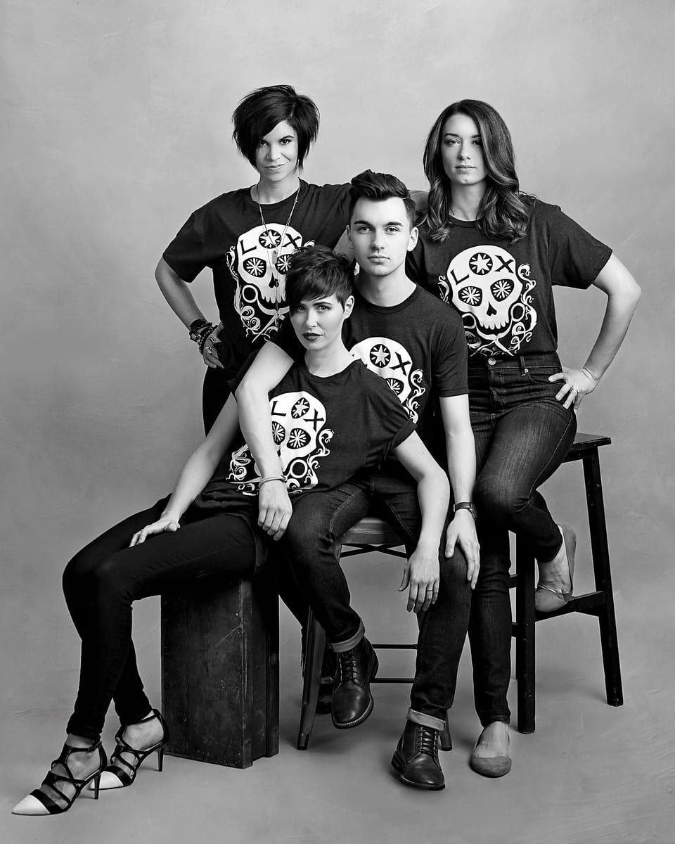 Four people in matching skull t-shirts and jeans, posing for a photo. Black and white.