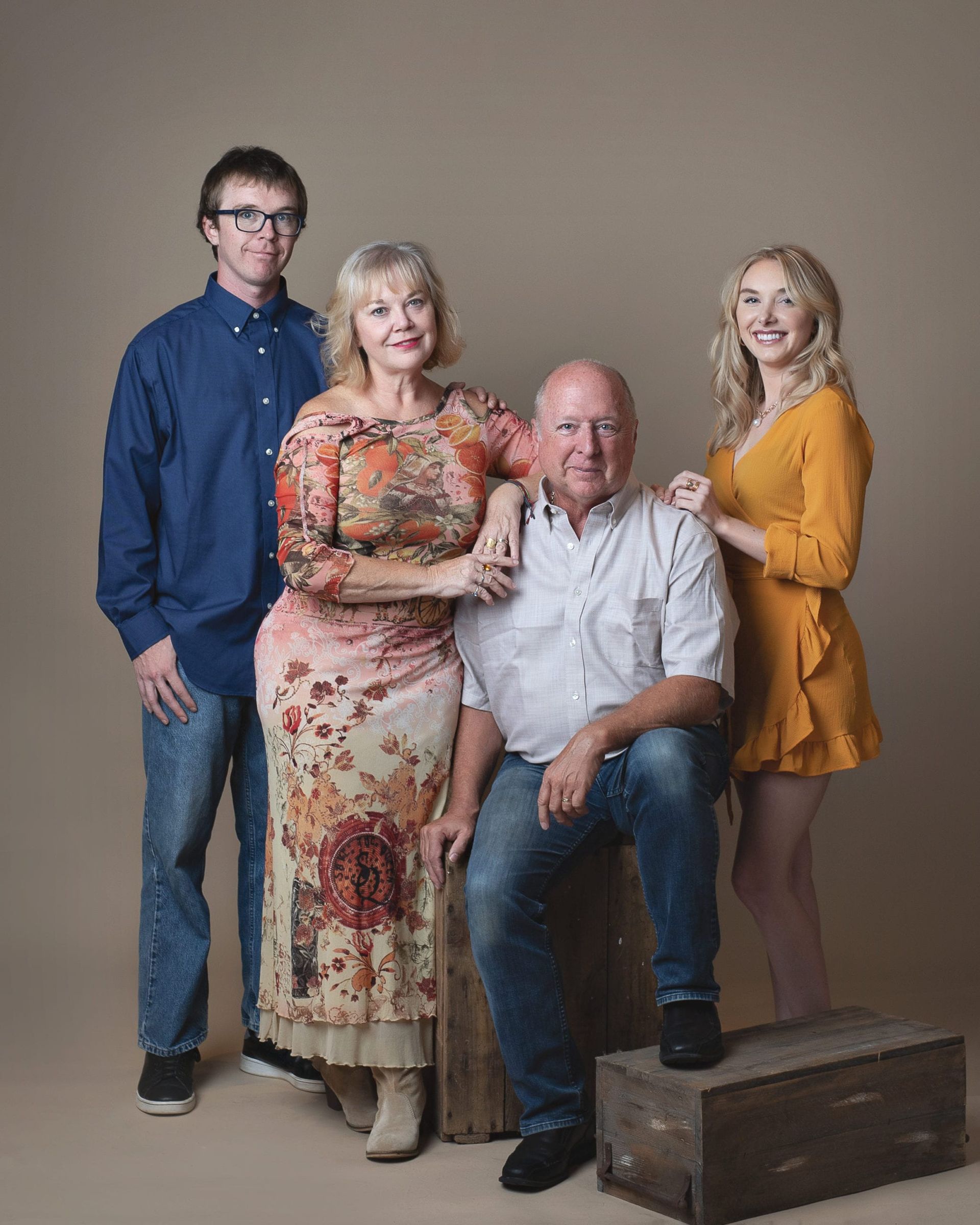 Family portrait: two parents, son, and daughter posing in front of a neutral backdrop.