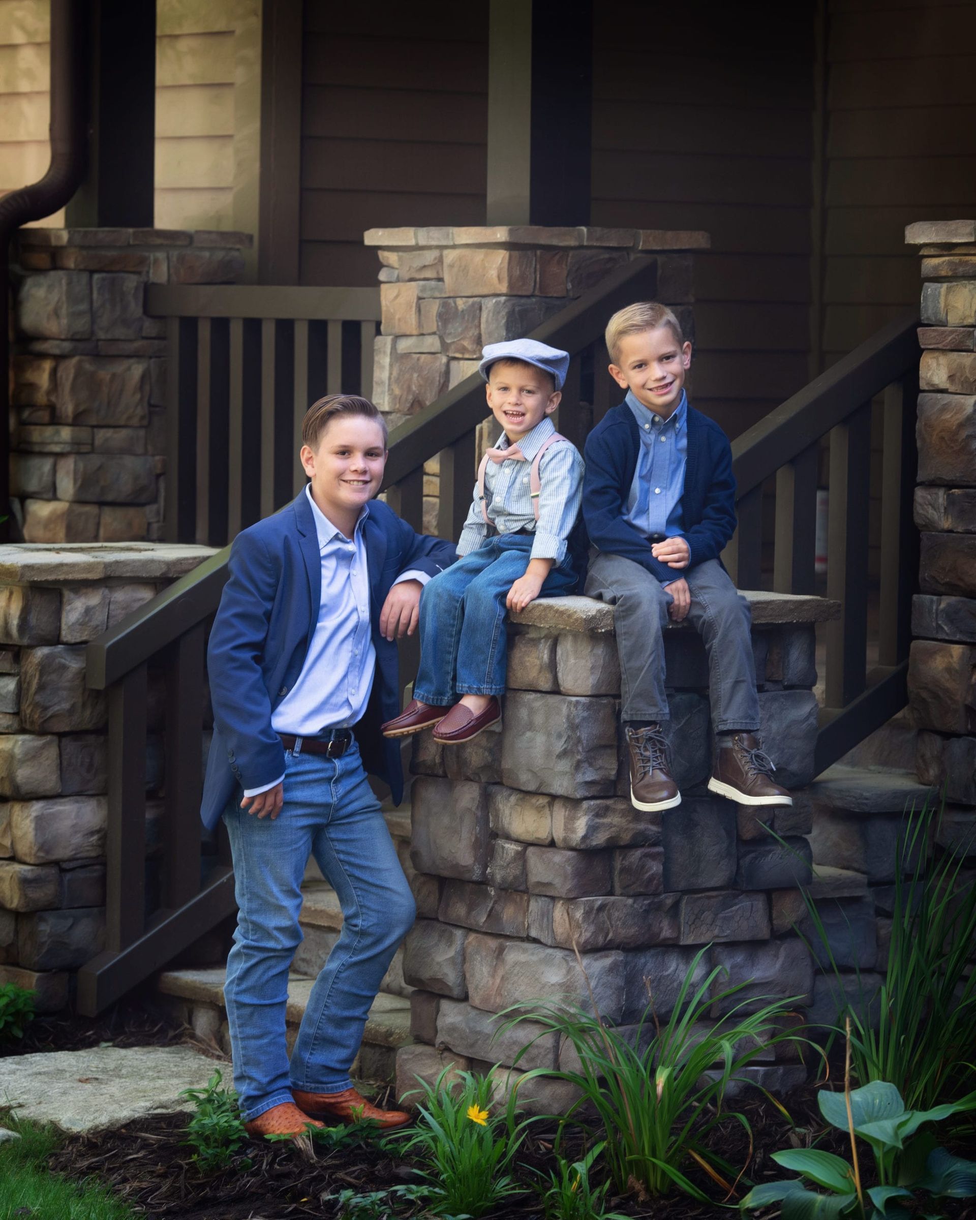 Three boys in formal attire pose on stone steps of a house.