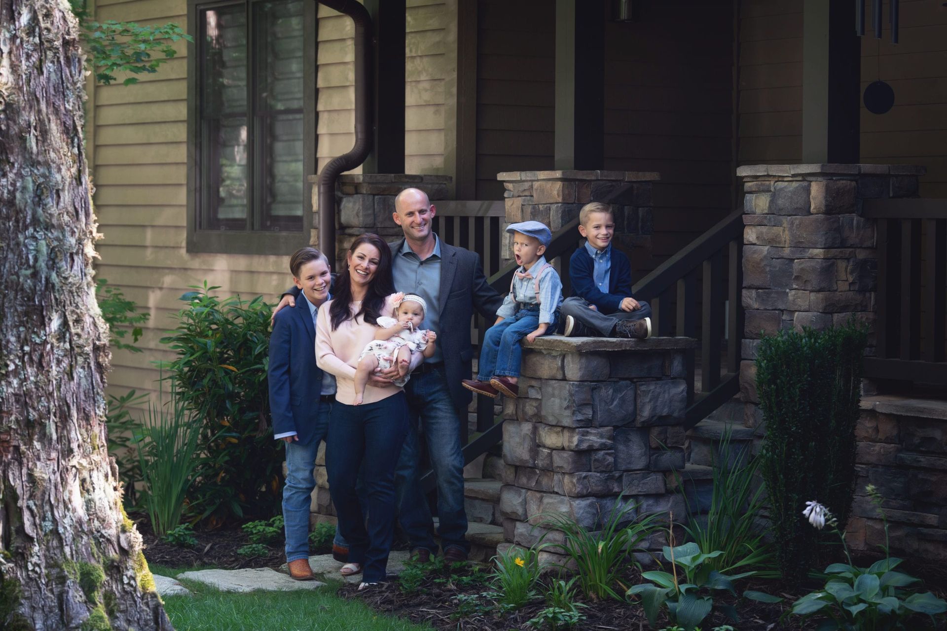Family of six poses on front porch of a home.