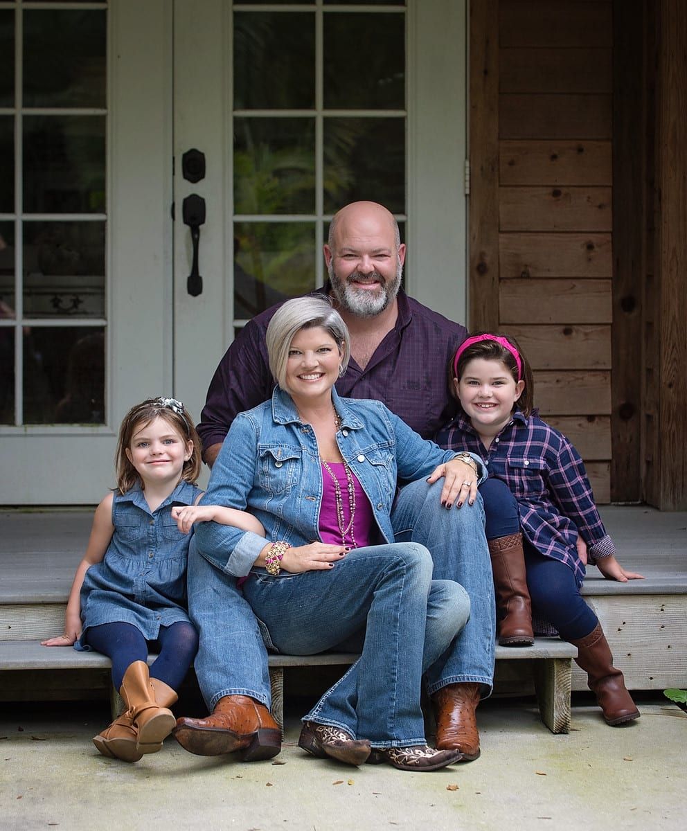 Family of four sitting on porch steps smiling.