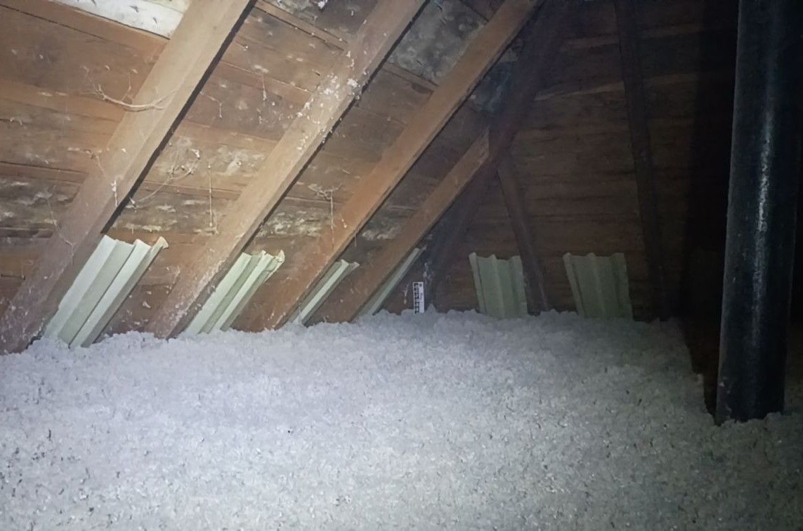 Attic space with spray foam insulation on the angled ceiling, a small skylight, and a concrete floor.