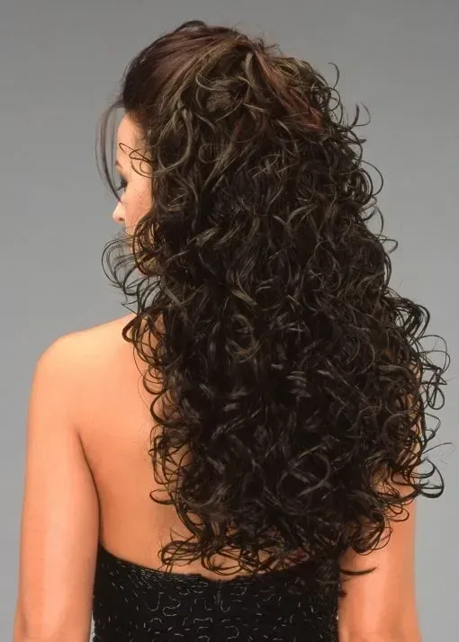 Woman with long curly dark hair shown from the back, wearing a black strapless top against a gray background