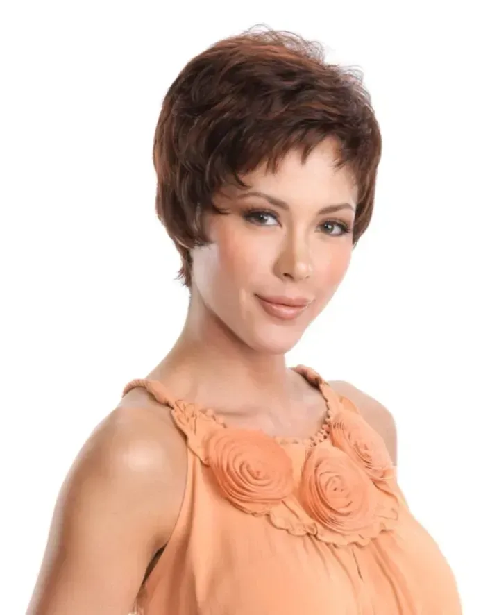 Woman with short brown hair wearing a peach blouse, posing against a white background.