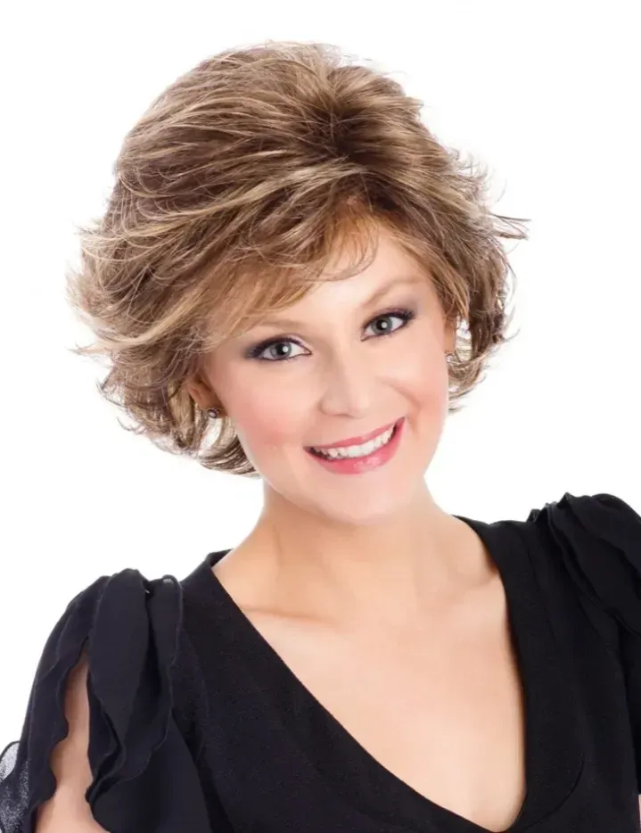 Smiling woman in a black dress with short layered blonde hair against a white background