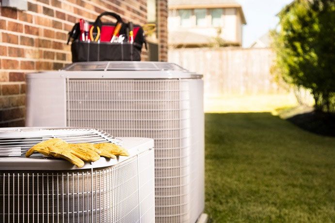 Integrity Energy Systems Two air conditioners are sitting next to each other in a backyard.