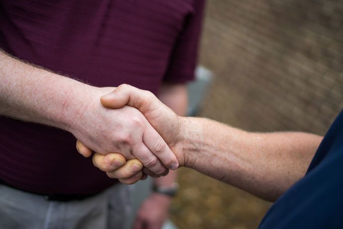  Integrity Energy Systems Two men are shaking hands in a close up of their hands.