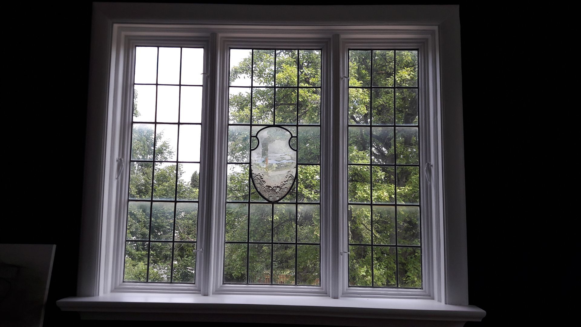 A stained glass window with a vase on the window sill.