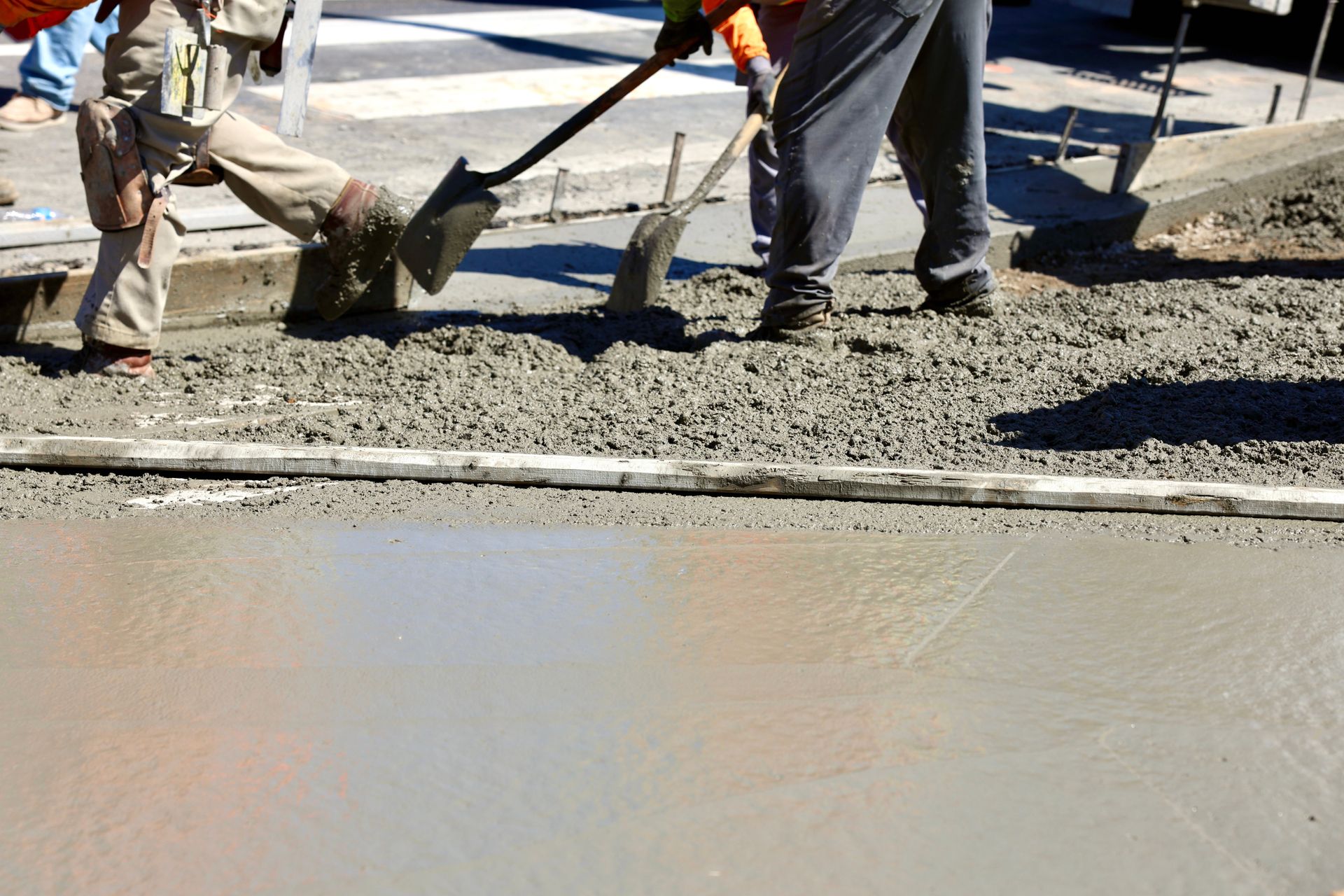 A man is using a shovel to spread concrete on the ground.