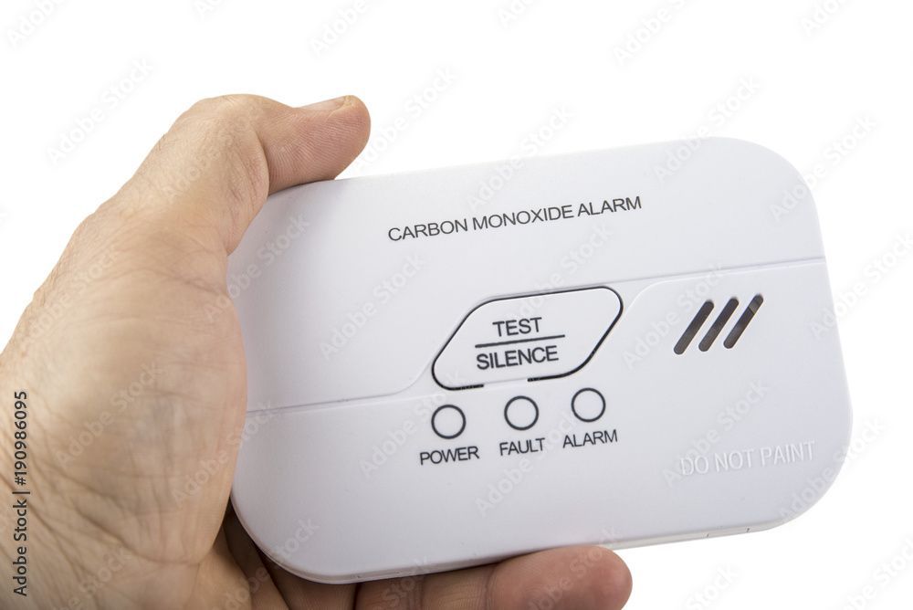 A person is holding a carbon monoxide alarm in their hand.