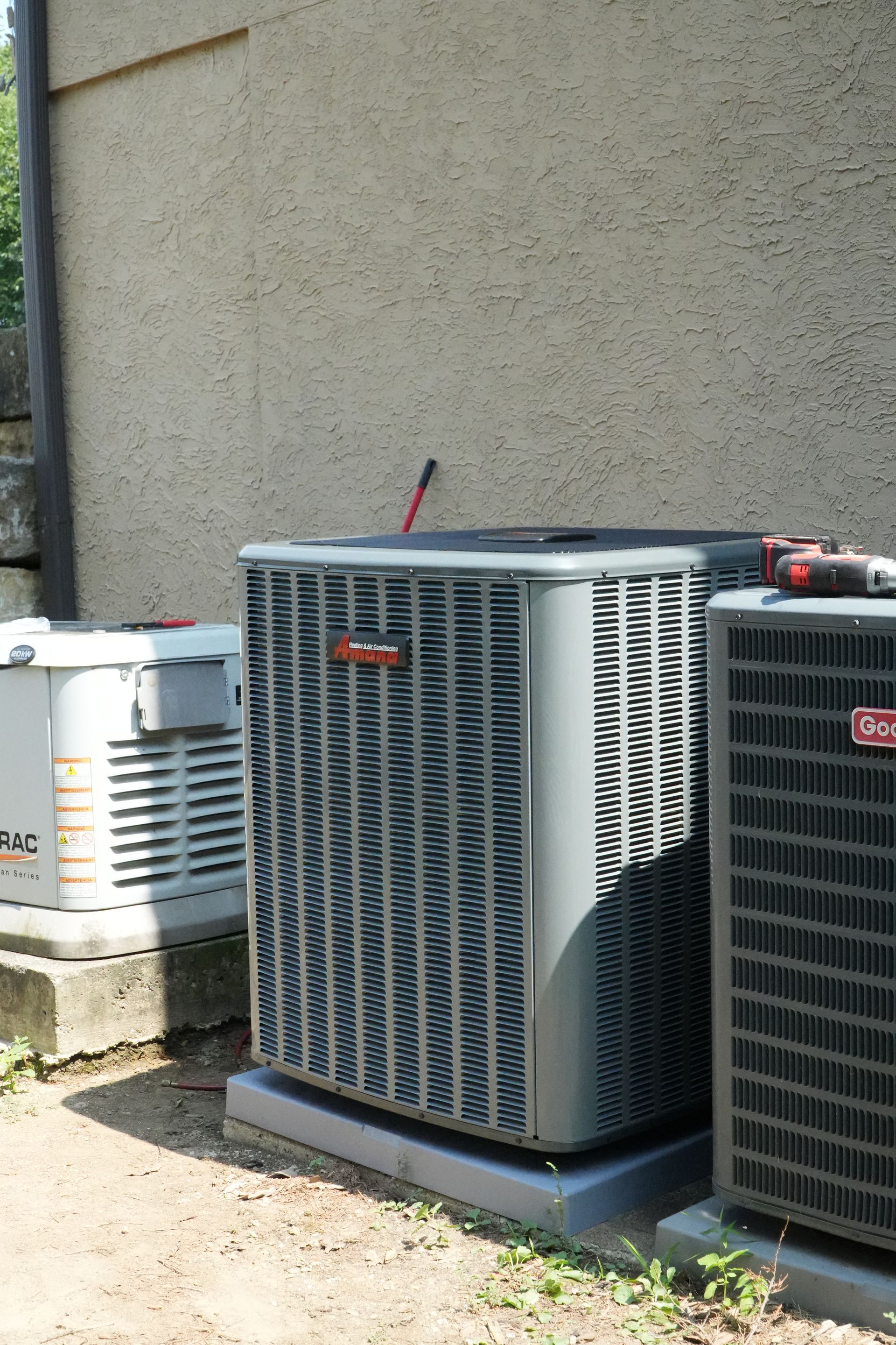 Amana outdoor air conditioner beside other equipment at a J F Denney job site.