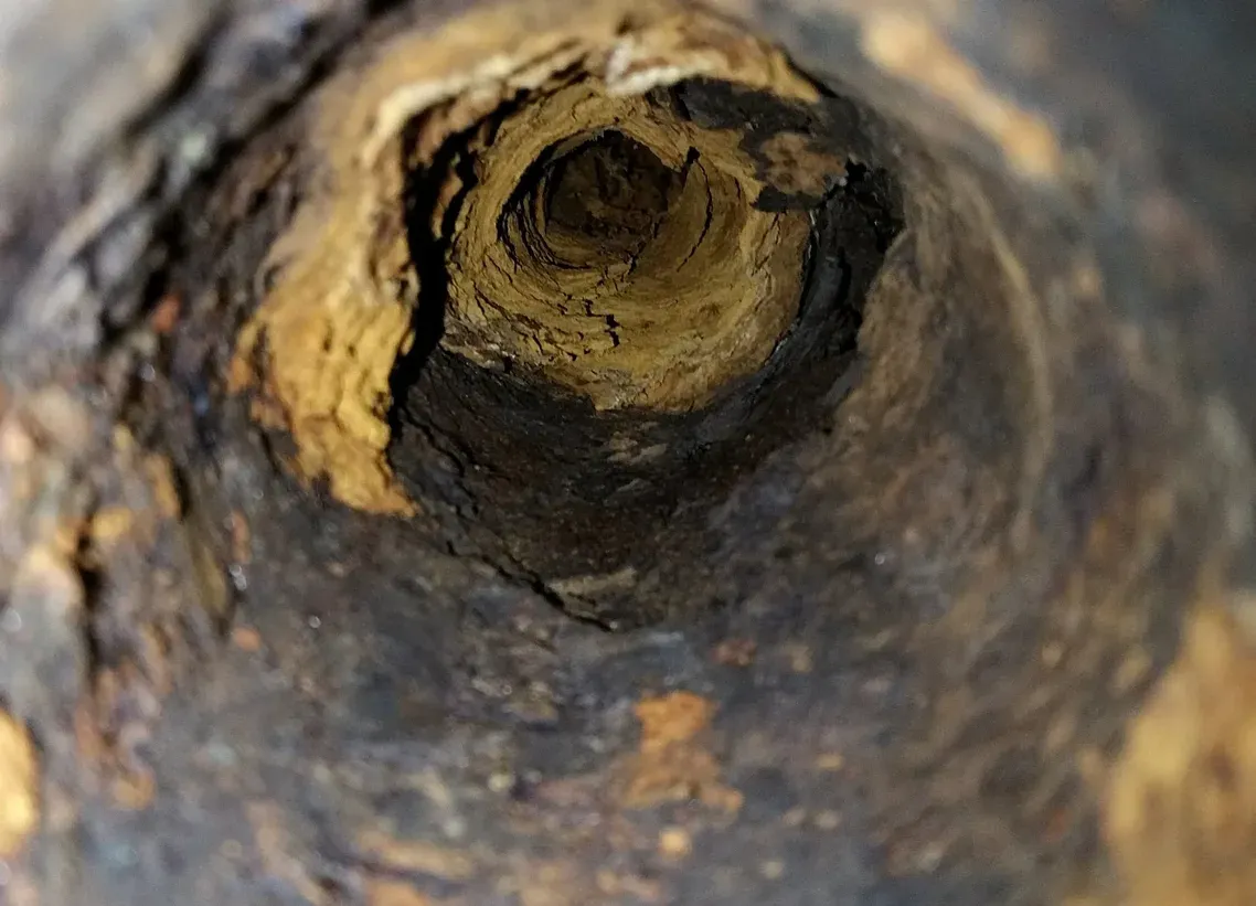 A close up of a rusty pipe with a hole in the middle.