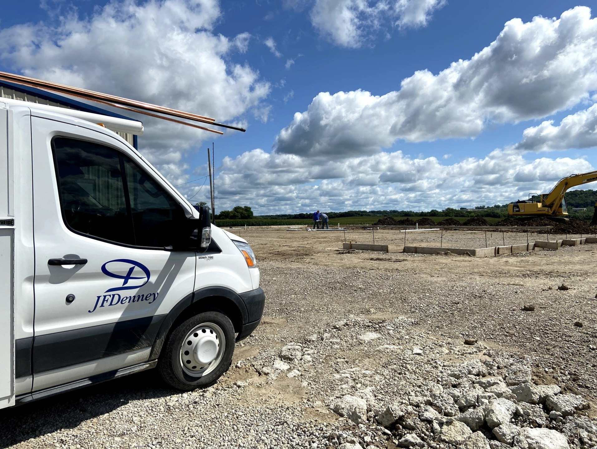 A white van is parked in a dirt field.