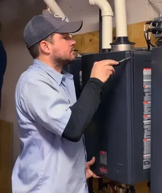 A man in a baseball cap is working on a heating system.