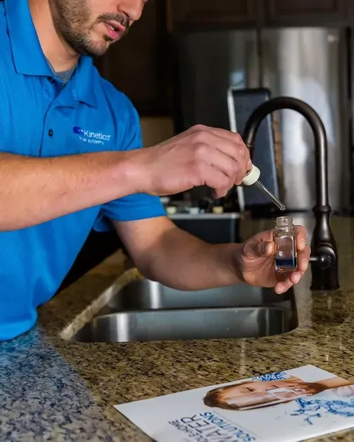 A man in a blue shirt is pouring liquid into a bottle