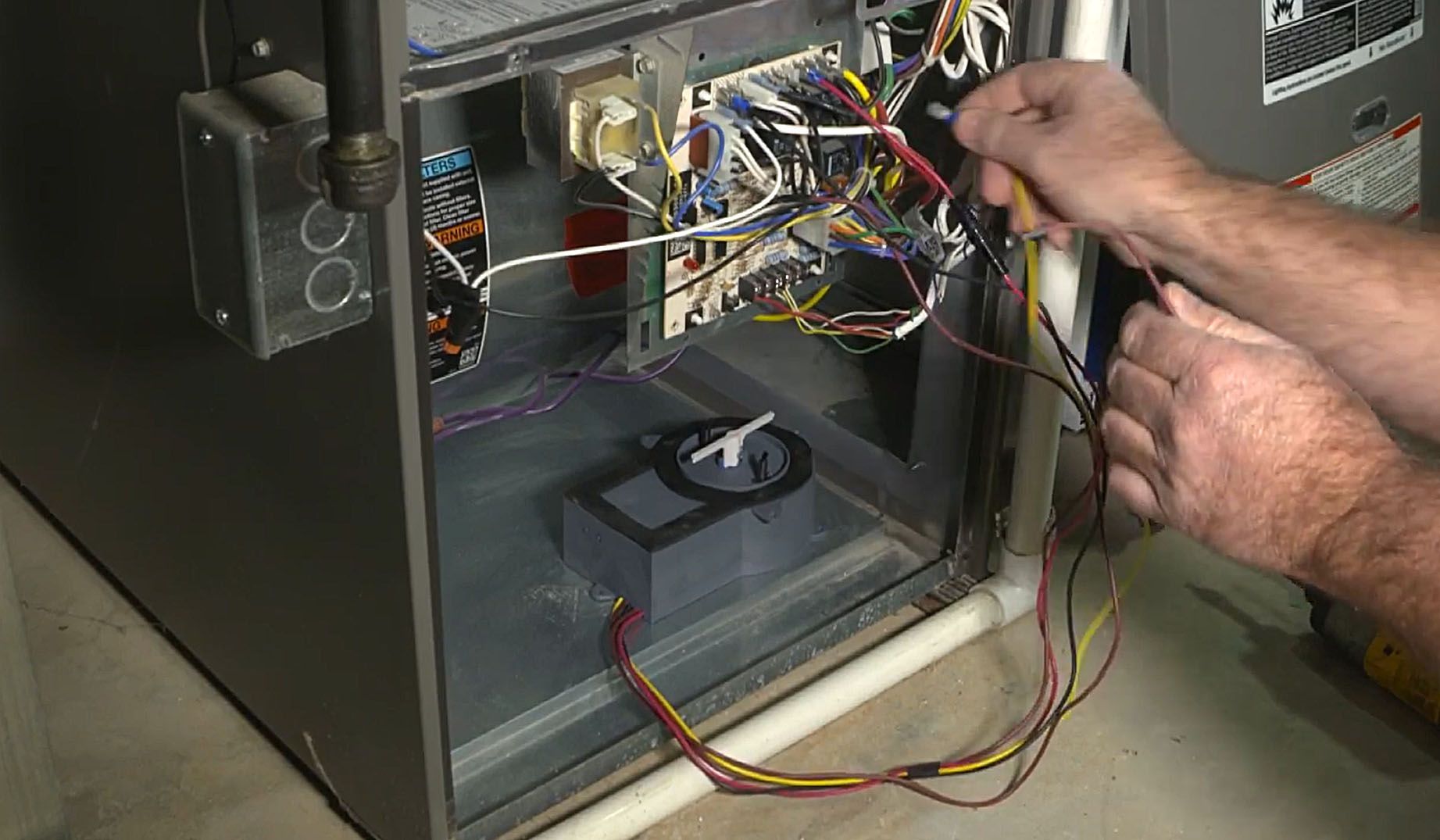 A man is working on an air conditioner with a voltage meter.
