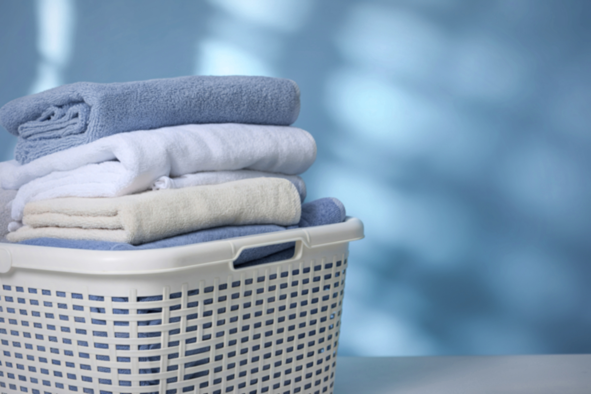 Laundry basket with folded white and blue towels against a blue background