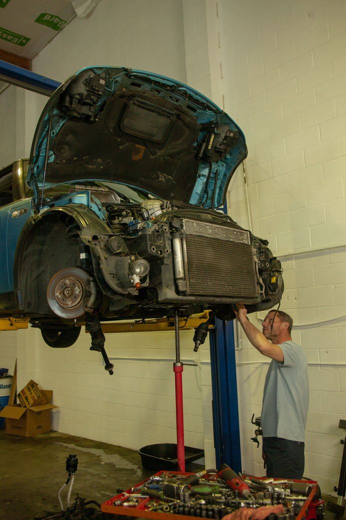 Mechanic working under a car raised on a lift in a garage | Bay's Auto Repair & Collision Services